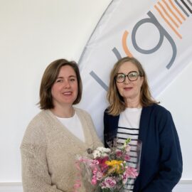 Two women on the photo, and one holding flowers.